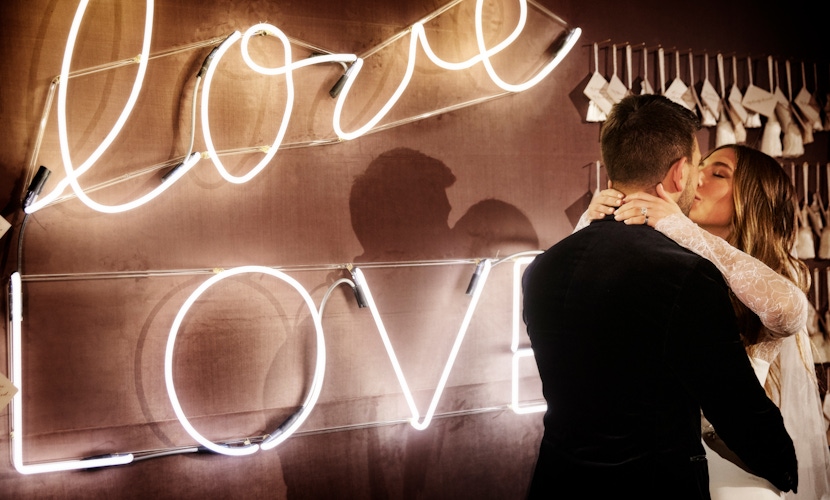 bride and groom and neon love light up sign