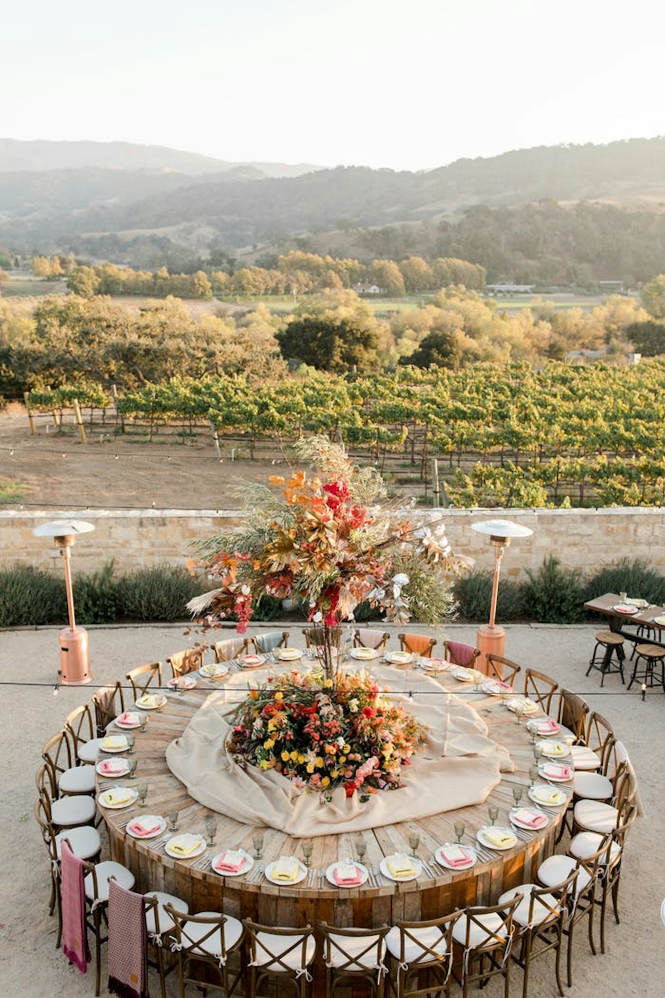 Round wooden wedding table with large floral centerpiece