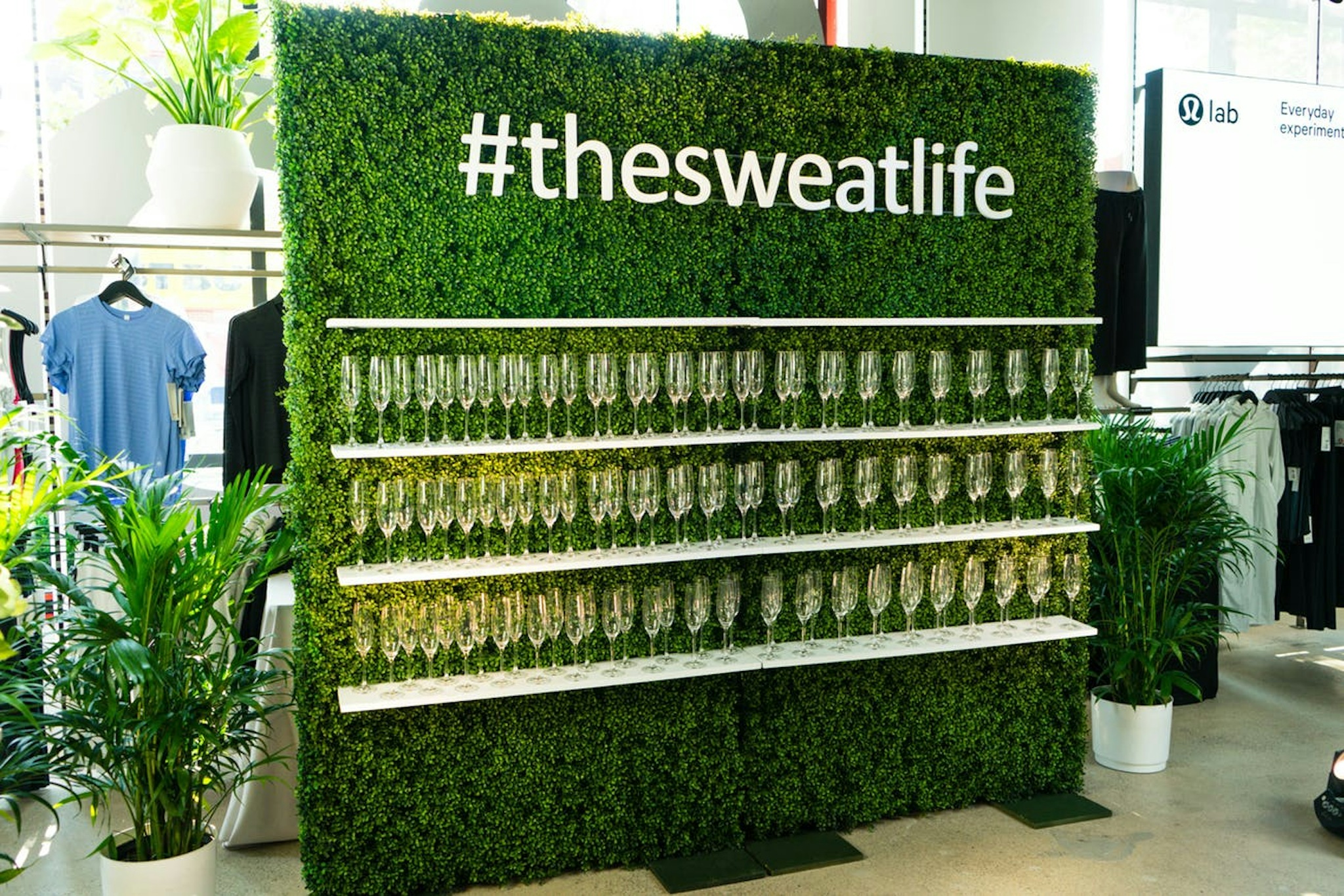 largest lululemon store opening in Chicago with a greenery wall of champagne and a #thesweatlife sign
