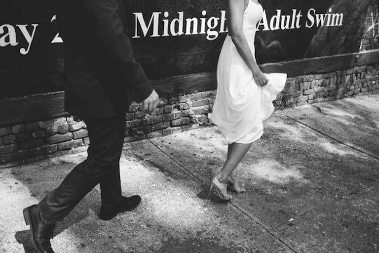 Black and white, shoulders down shot of bride walking in front of the groom on sidewalk | PartySlate