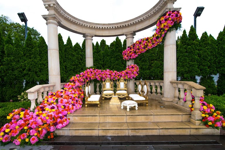 Wedding alter with pillars decked in cascading pink blooms | PartySlate