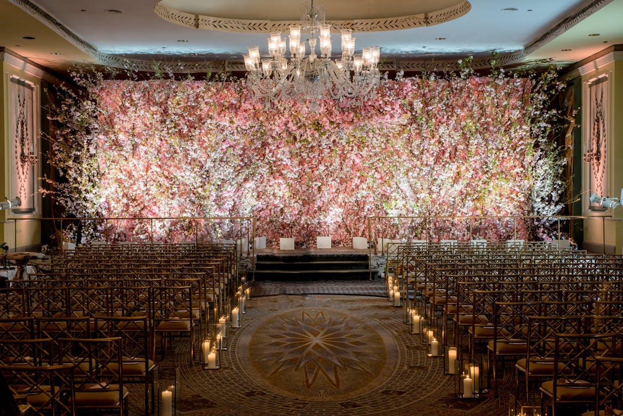Wedding ceremony space with rose-floral backdrop | PartySlate