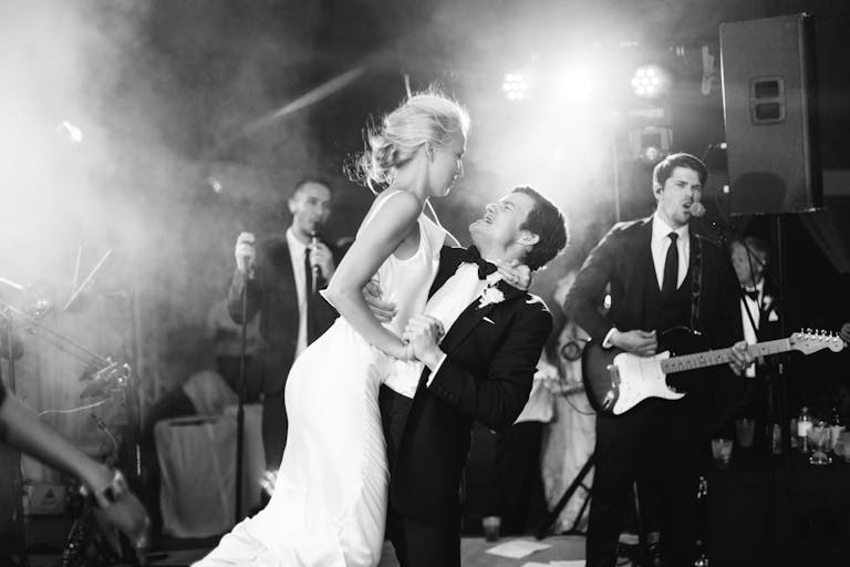 Black-and-white photo of groom lifting up bride in front of band