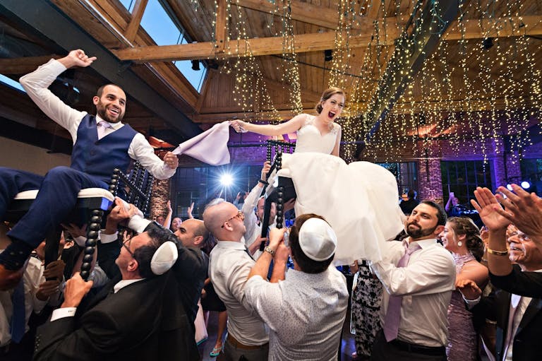 Bride and groom lifted up on chairs during horah