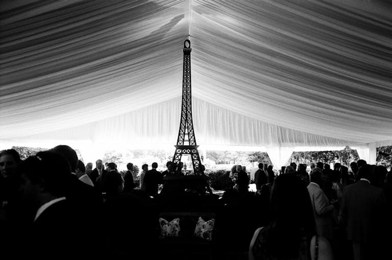 Black and white photo of tent ed dance floor with Eiffel Tower statue | PartySlate