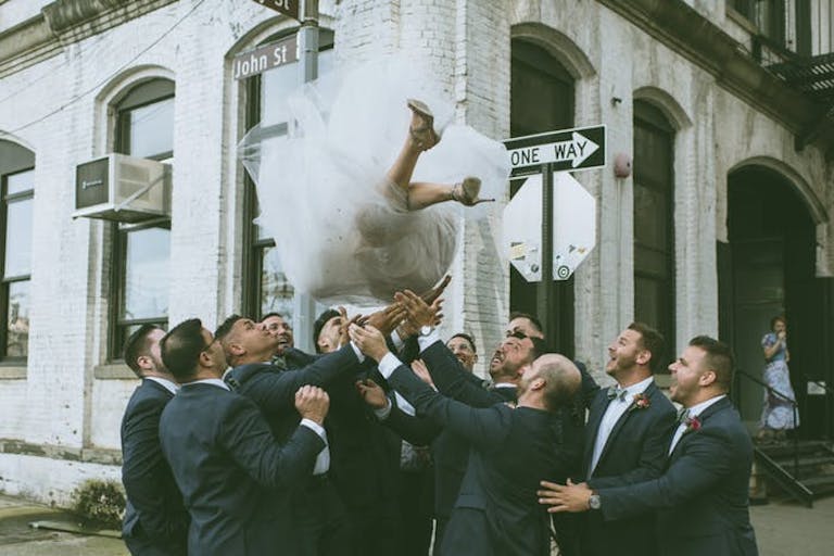 Groomsman throw bride into the air and catch | PartySlate