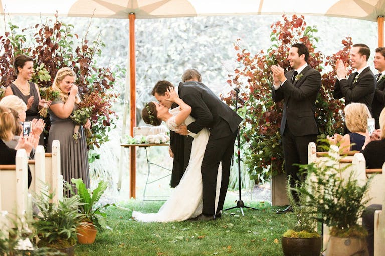 Bride and groom kiss at the alter at outdoor tent wedding | PartySlate