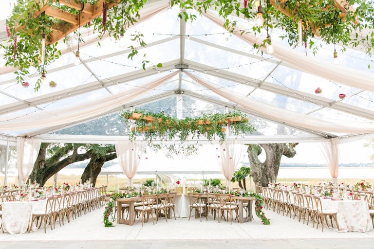 Tented reception area with vine covered ladders hanging overhead of long tables | PartySlate