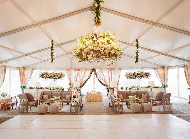 Tented dance floor area with floral chandelier and dusty purple furniture | PartySlate