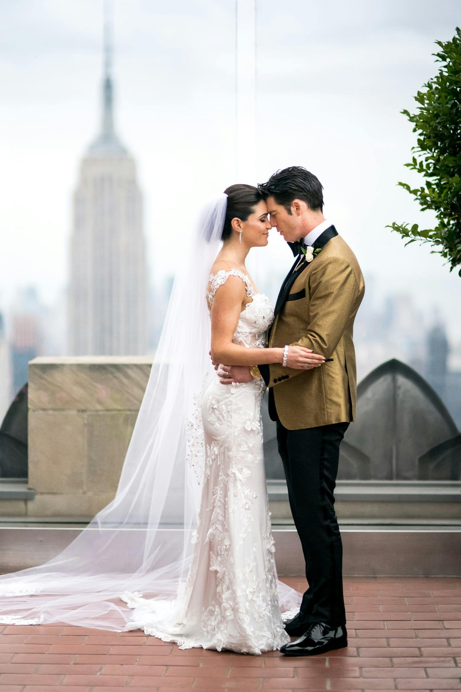 couple posing with faint image of Empire State Building in background
