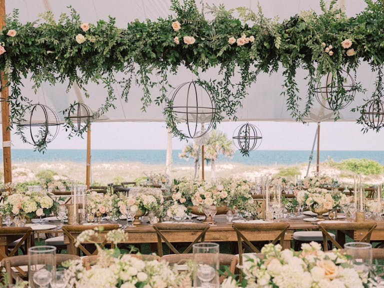 Ocean side outdoor reception tables with floral arrangements | PartySlate