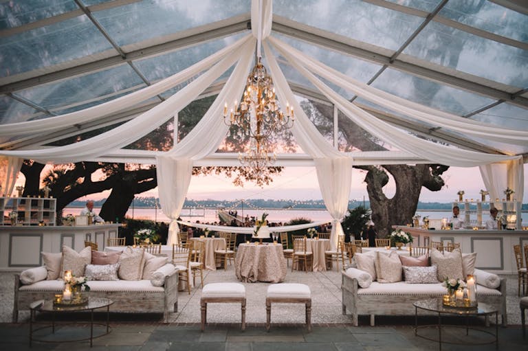 Cocktail area with white furniture with tent tapestries and glass window coverings | PartySlate