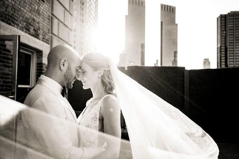 Black and white photo of couple embracing with New York City skyline in the background | PartySlate