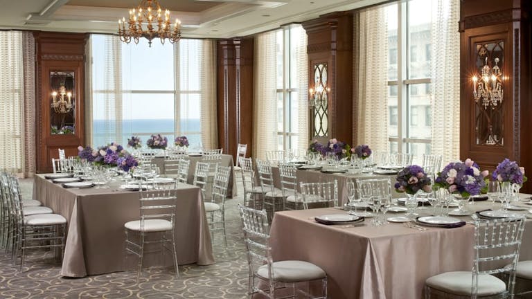 Luxurious ballroom with chandeliers and purple floral centerpieces at the Four Seasons in Chicago Illinois | PartySlate