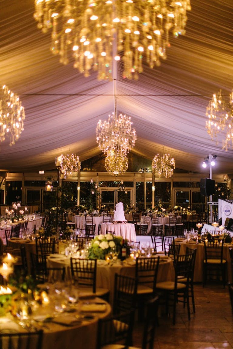 Tented wedding at Galleria Marchetti with chandeliers and floral centerpieces | PartySlate