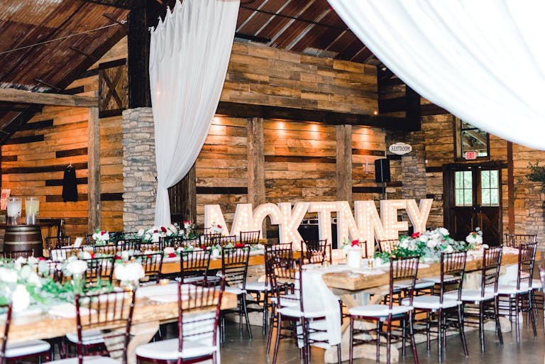 barnyard reception area with white drapery and monogrammed signage | PartySlate