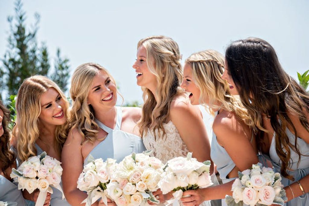Bridesmaids and bride pose holding bouquets | PartySlate