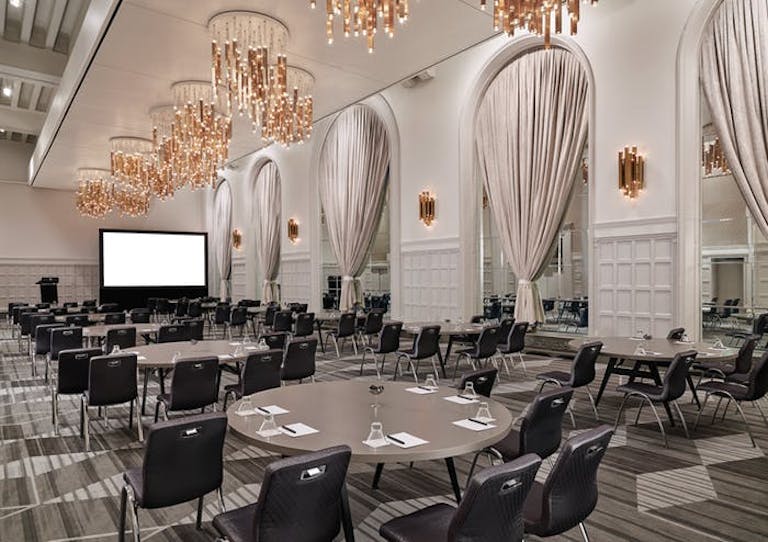 Chicago City Center Event Space with modern chandeliers and chairs and tables facing a TV screen | PartySlate