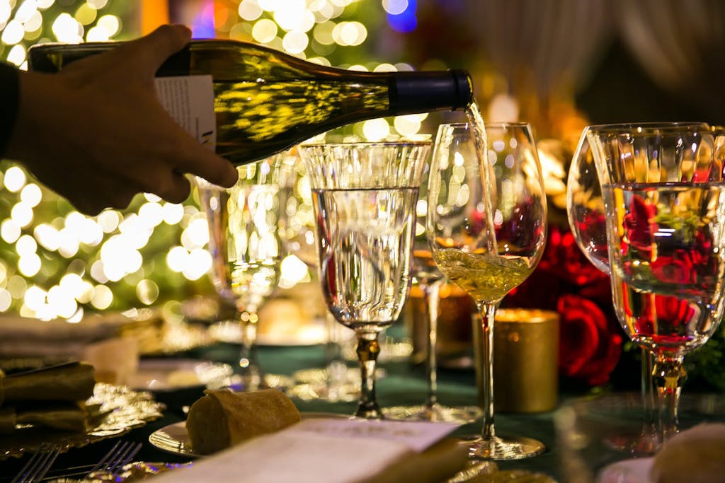 cropped photo of hand pouring a glass of white wine | PartySlate