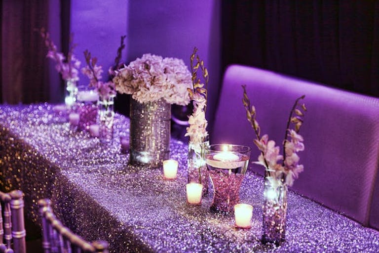 Purple floral centerpieces matching the glittery table cloth at shimmery Bat Mitzvah | PartySlate