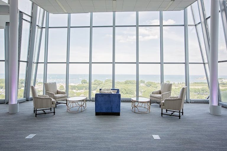 Open space with four comfortable chairs and floor to ceiling windows with view of Grant Park at Venue SIX10 | PartySlate