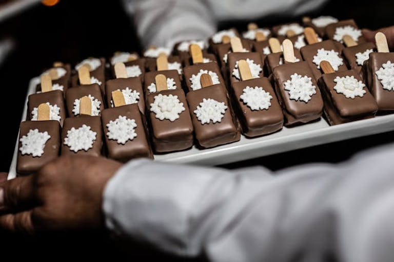 Caterer holding tray with festive chocolate coated ice cream with fondant snowflake | PartySlate