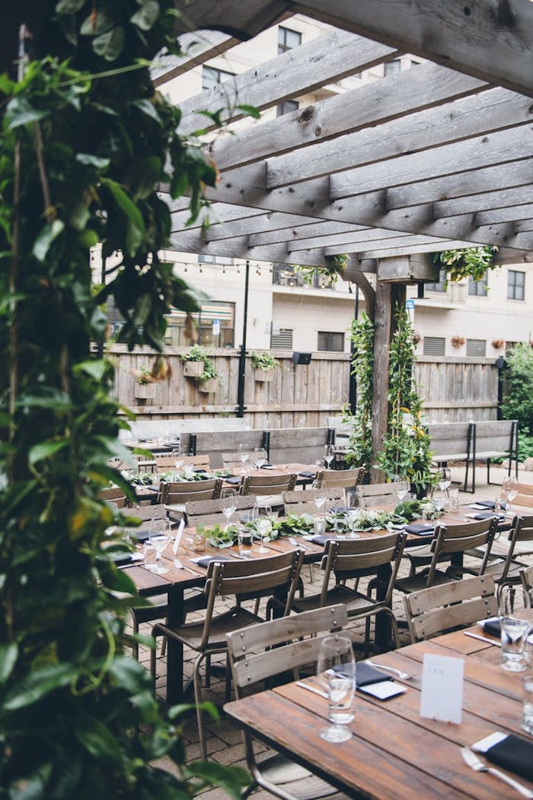 Wooden tables and chairs at patio space embellished with vibrant vines | PartySlate