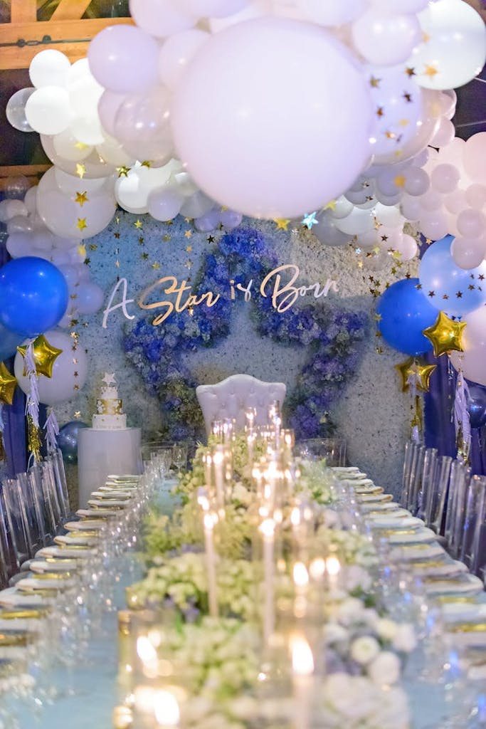 Baby shower dining table with candles and "A Star is Born" sign under blue and white balloons and gold stars | PartySlate