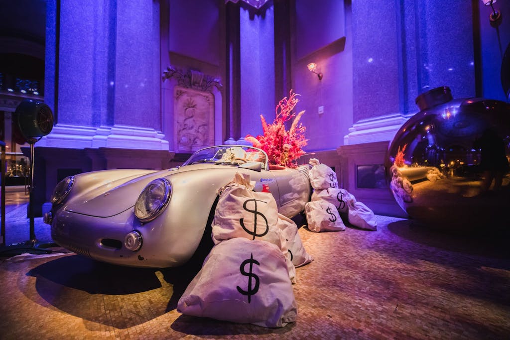 Photo backdrop of vintage car and giant bags of money | PartySlate