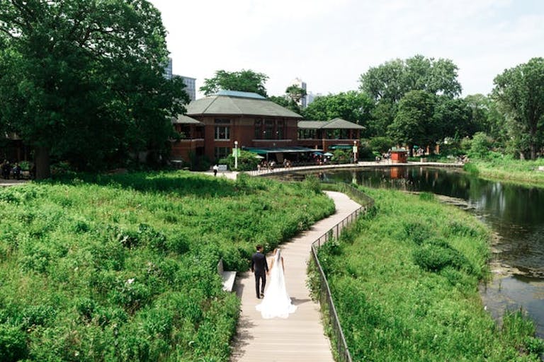 Bride and groom on green winding pathway at Cafe Brauer at Lincoln Park Zoo | PartySlate