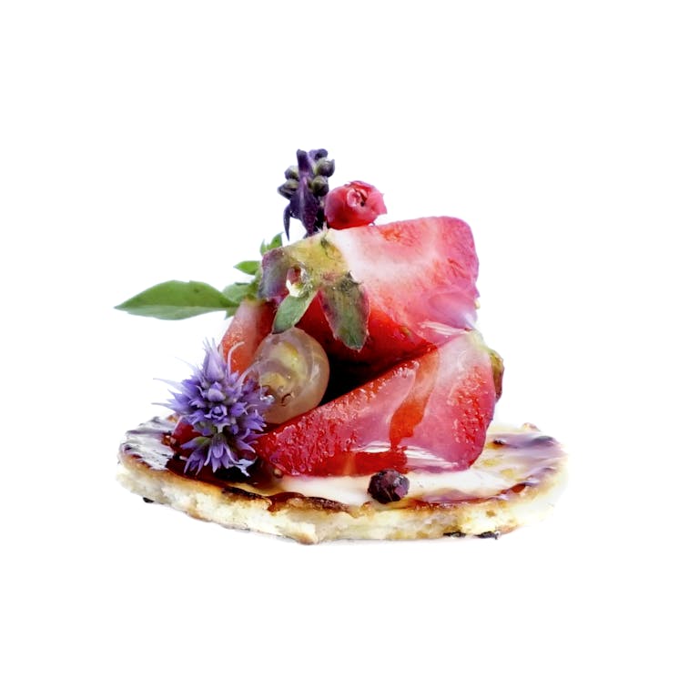 passed bite of strawberry and edible florals on cracker
