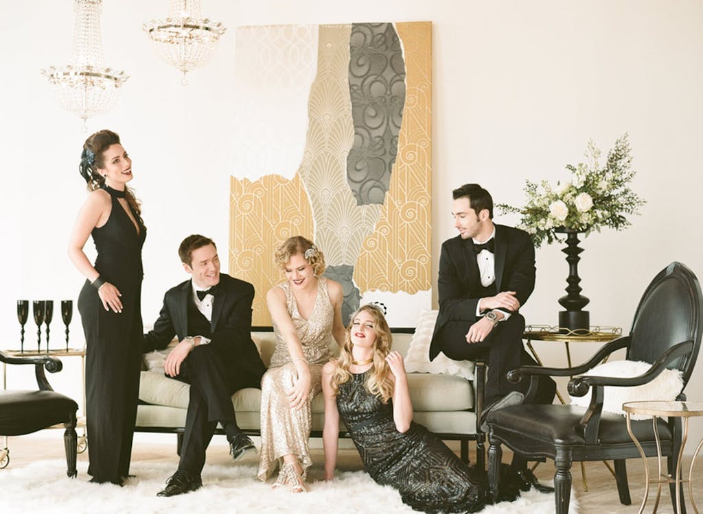 Group of friends lounging in Art Deco costumes at a wedding rehearsal dinner party | PartySlate
