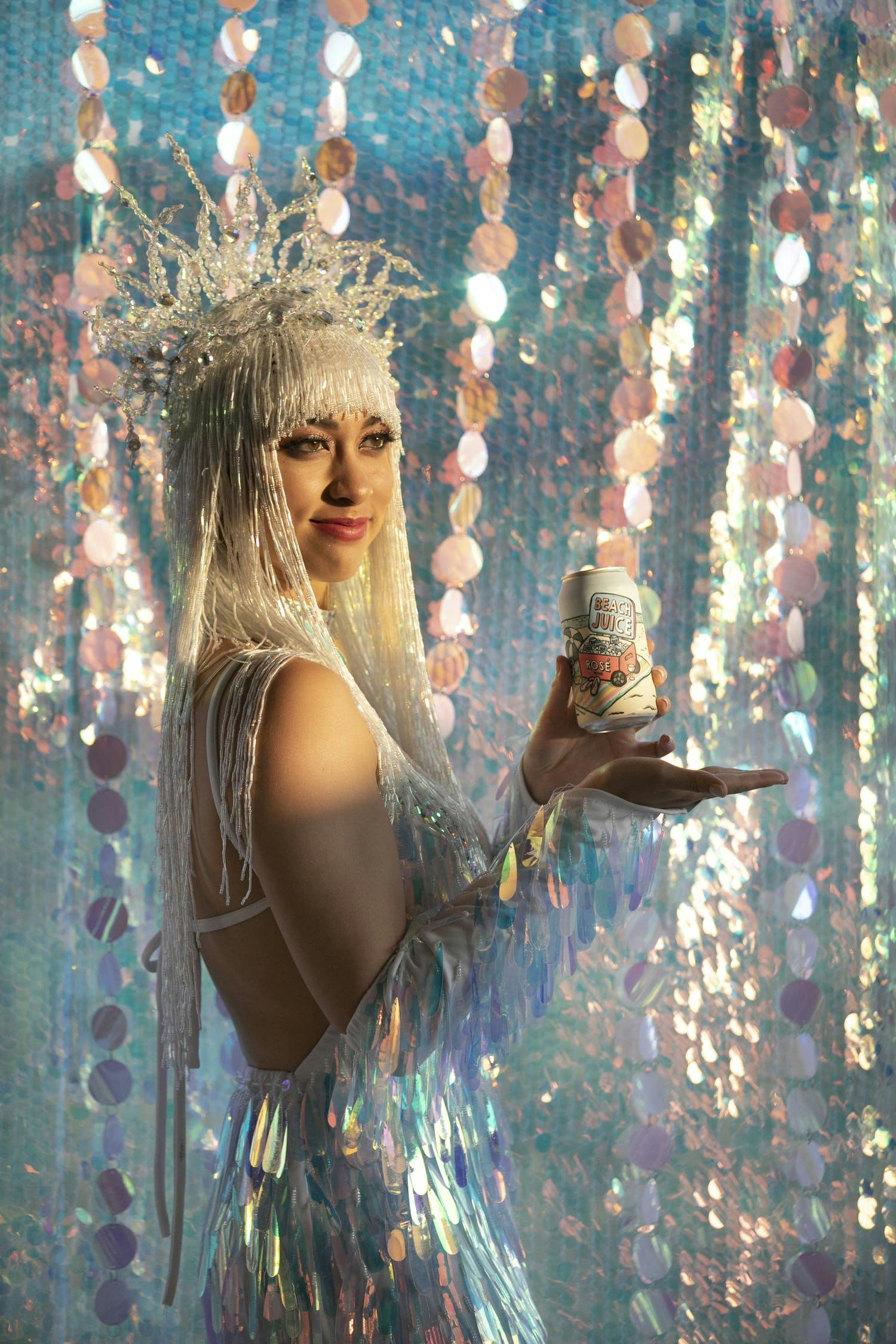 Woman holding beer can against a backdrop of iridescent décor