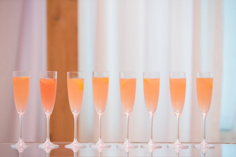 eight champagne glasses filled with rosé.
