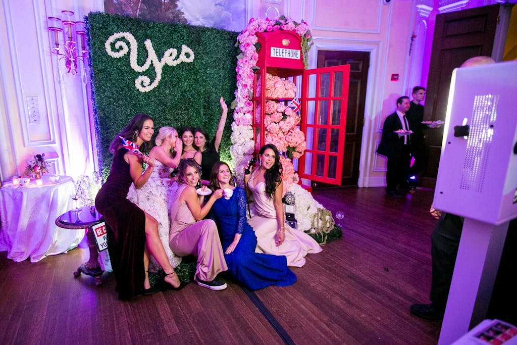 Guests posing in front of boxwood backdrop with "yes" signage