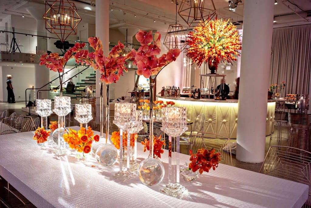 Banquet table with orange and hot pink florals at a wedding rehearsal dinner party