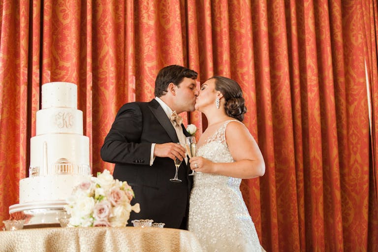 bride and groom kissing in front of wedding cake