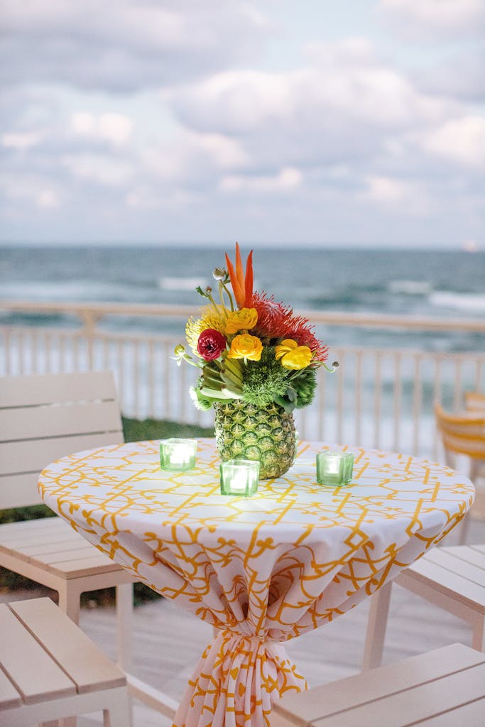Cocktail table with green tea lights and pineapple centerpiece at a wedding rehearsal dinner party | PartySlate