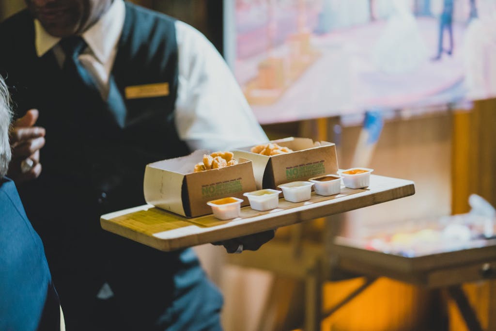 cropped photo of server and tray of small bites