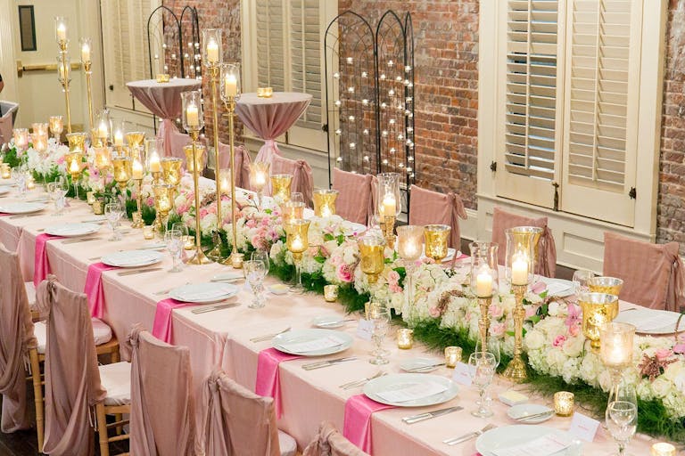 Tablescape with white floral table arrangement, blush table cloth, and bright pink napkins