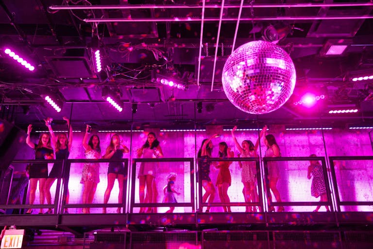 girls on warehouse balcony with pink uplighting and disco balls