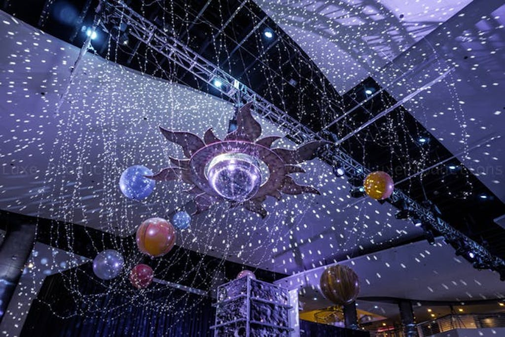 a solar system hangs above the crowd with silver tinsel around simulating a star filled sky. 