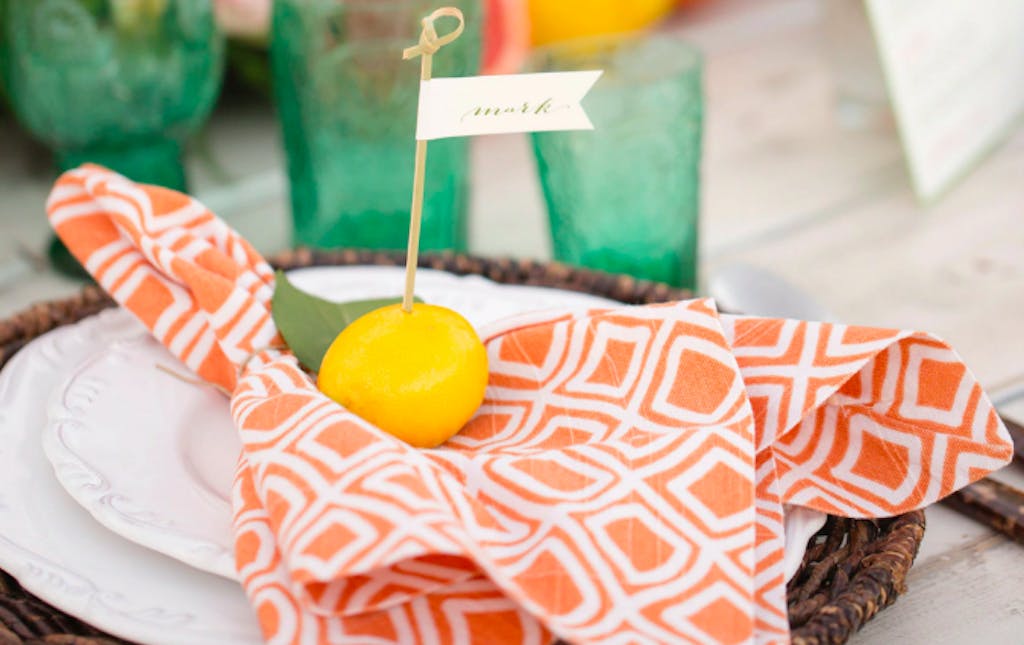 orange printed napkin topped by a lemon and seating name tag