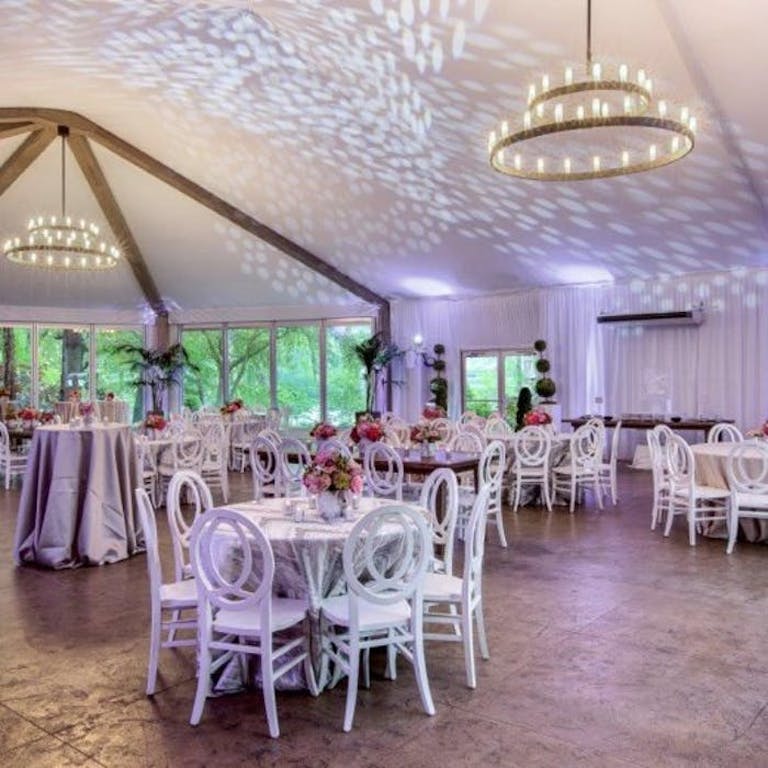 White room with low roof and candle chandeliers handing down over white tables and chairs