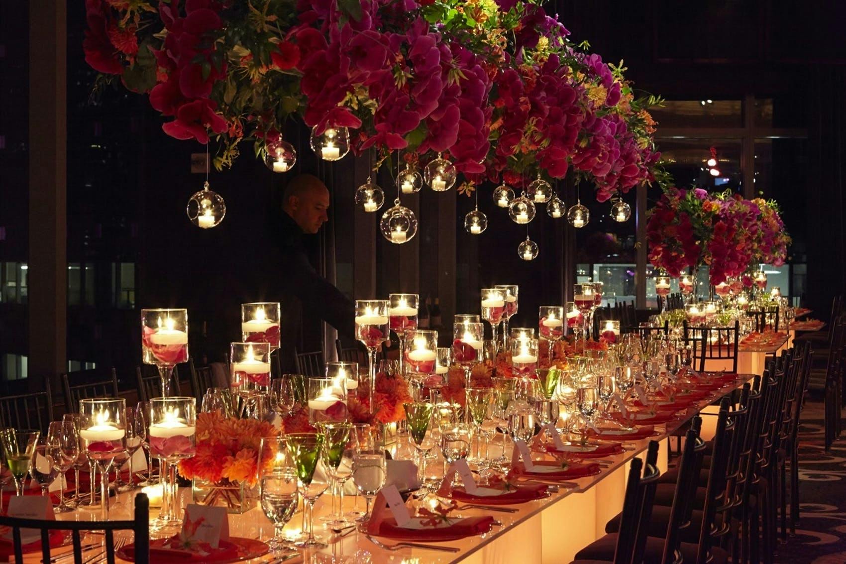 Table with candles in red wax throughout and rad roses hanging above