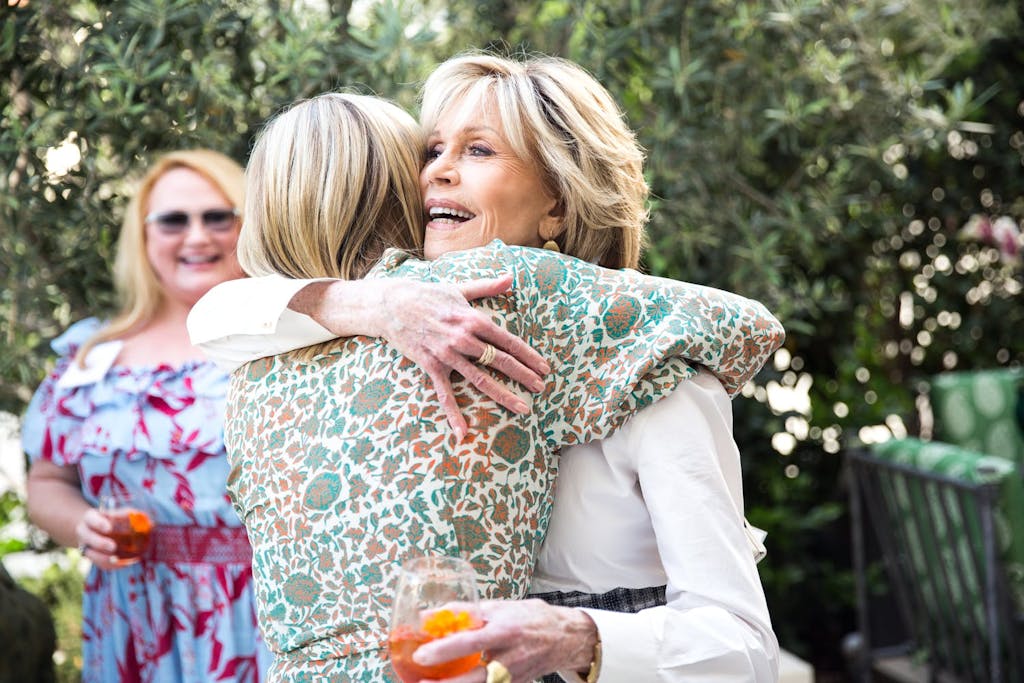 two women hug as they greet each other at an outdoor dinner party