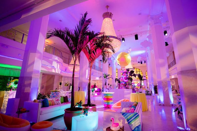 Room with purple hue and white pillars and mini palm trees