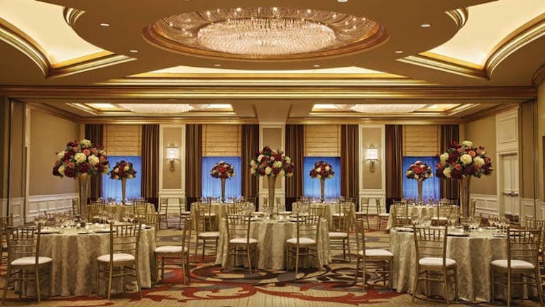 Large room with fancy tables with red and white flower centerpieces