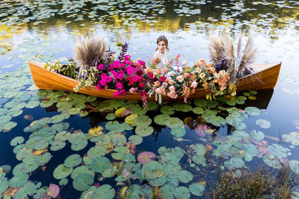 Woman sitting in a flower-filled canoe in a lily pond