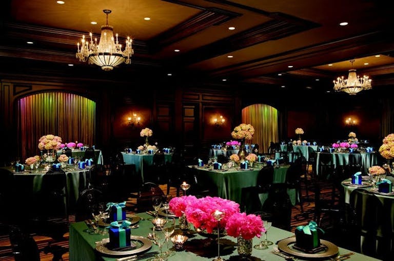 Dark room with green tables with pink flowers centerpieces